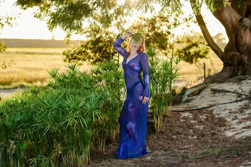 High-class escort in an elegant dress in a refined outdoor setting with soft natural light