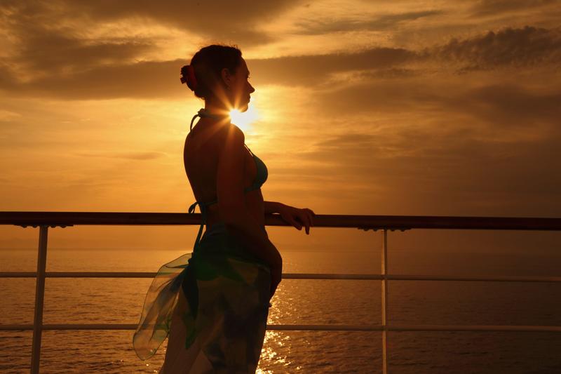 High-end escort on a luxury cruise ship deck during sunset, reflecting discreet cruise travel companionship